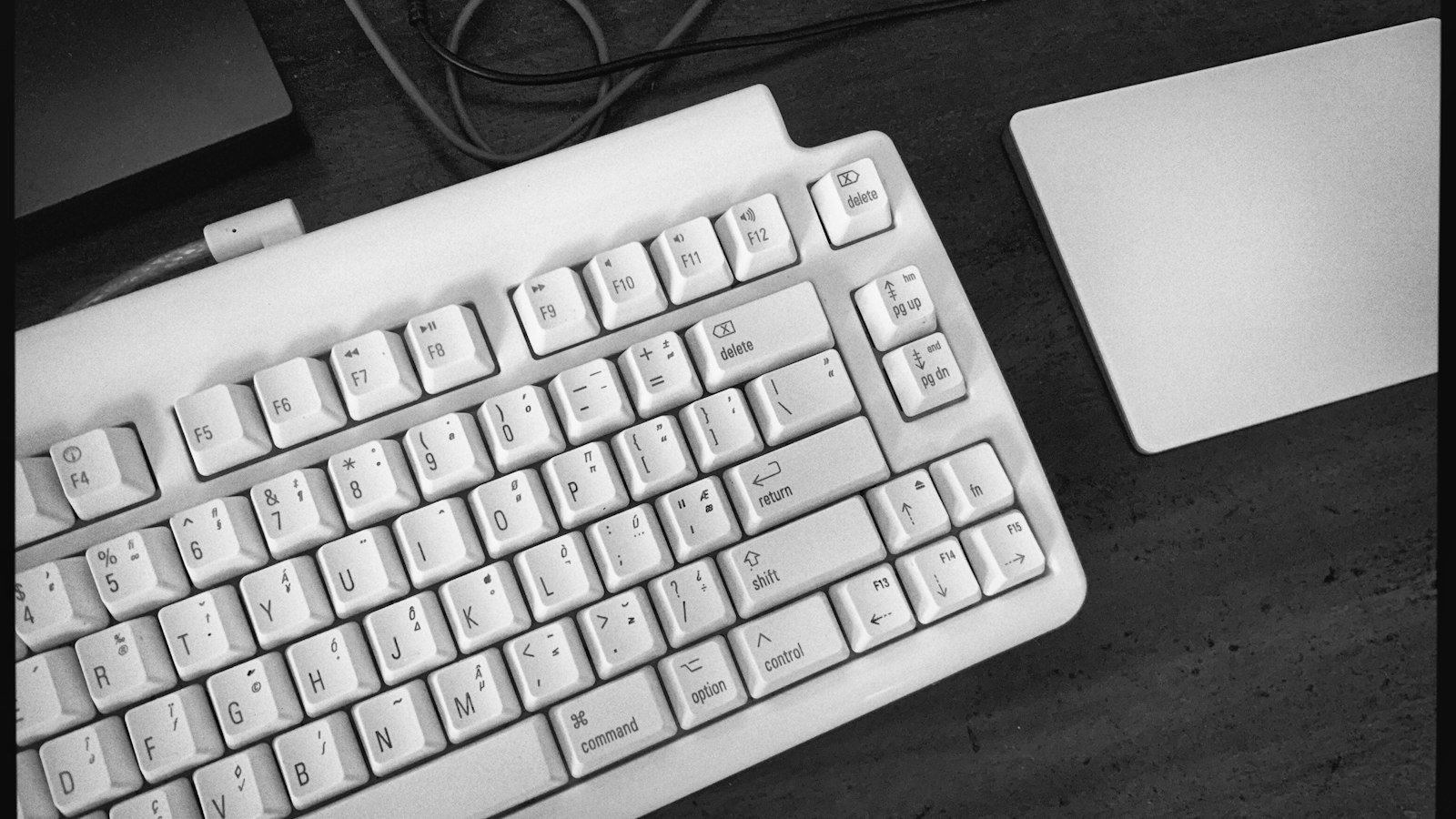 A white keyboard with command and option keys next to a trackpad on a desk