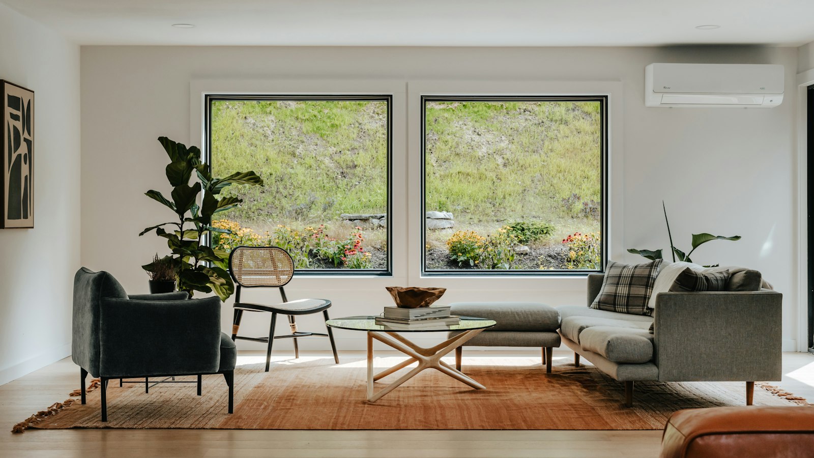 A bright living room with two large square windows looking out on a garden